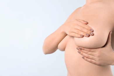 Woman checking her breast and space for text on white background, closeup