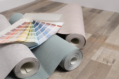 Photo of Wall paper rolls and color palette on wooden floor