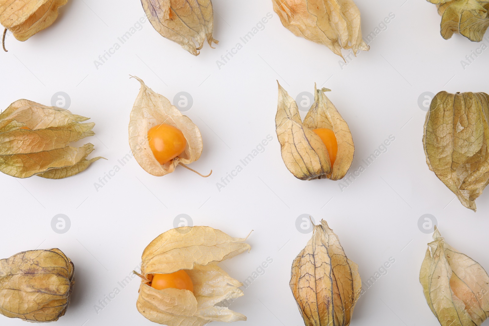 Photo of Ripe physalis fruits with calyxes on white background, flat lay