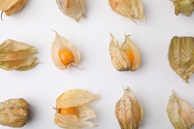 Ripe physalis fruits with calyxes on white background, flat lay