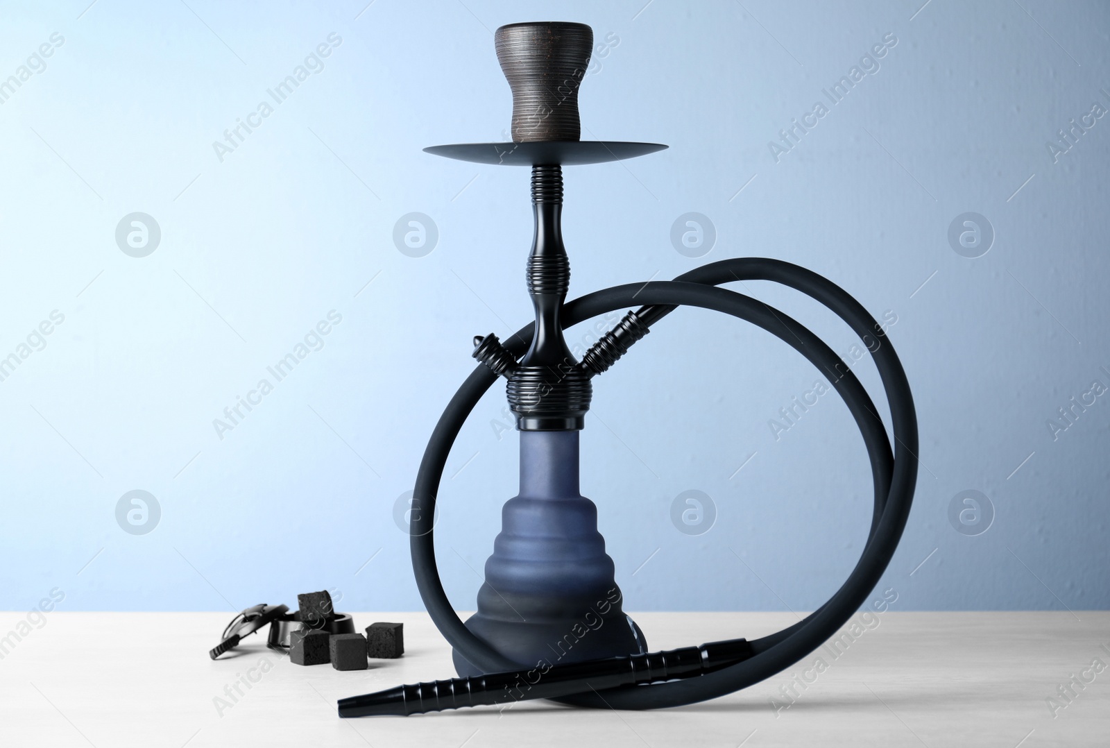 Photo of Traditional hookah on white table against light blue background