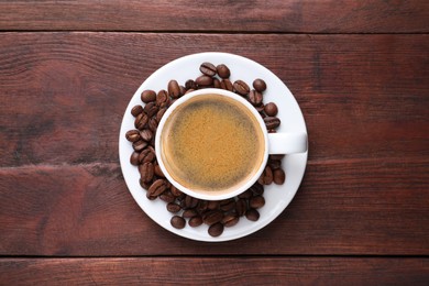 Cup of hot aromatic coffee and roasted beans on wooden table, top view