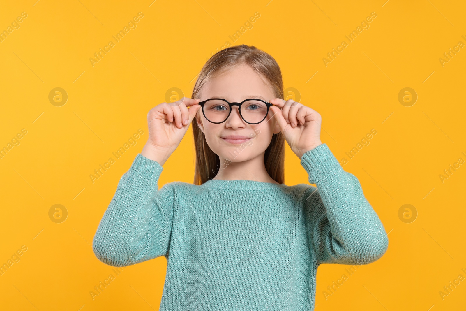Photo of Cute girl in glasses on orange background