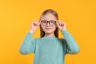 Photo of Cute girl in glasses on orange background