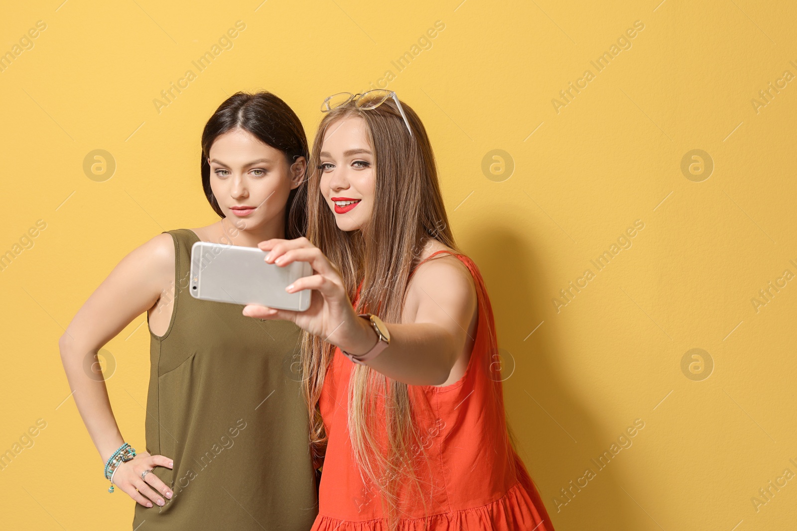 Photo of Attractive young women taking selfie on color background