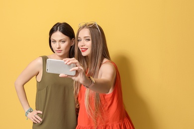 Attractive young women taking selfie on color background