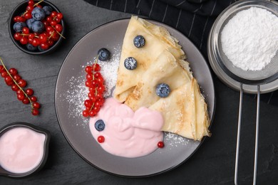 Delicious crepes with natural yogurt, blueberries and red currants on dark grey table, flat lay