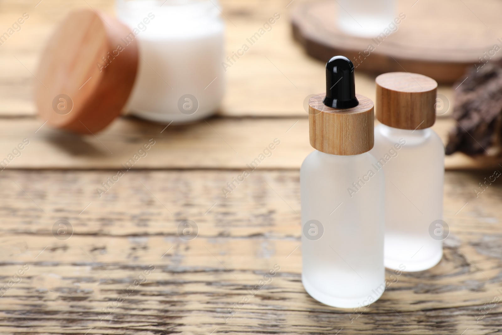 Photo of Bottles of essential oil on wooden table, closeup. Space for text