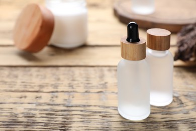 Photo of Bottles of essential oil on wooden table, closeup. Space for text