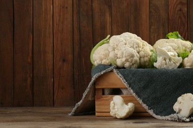 Crate with cut and whole cauliflowers on wooden table. Space for text