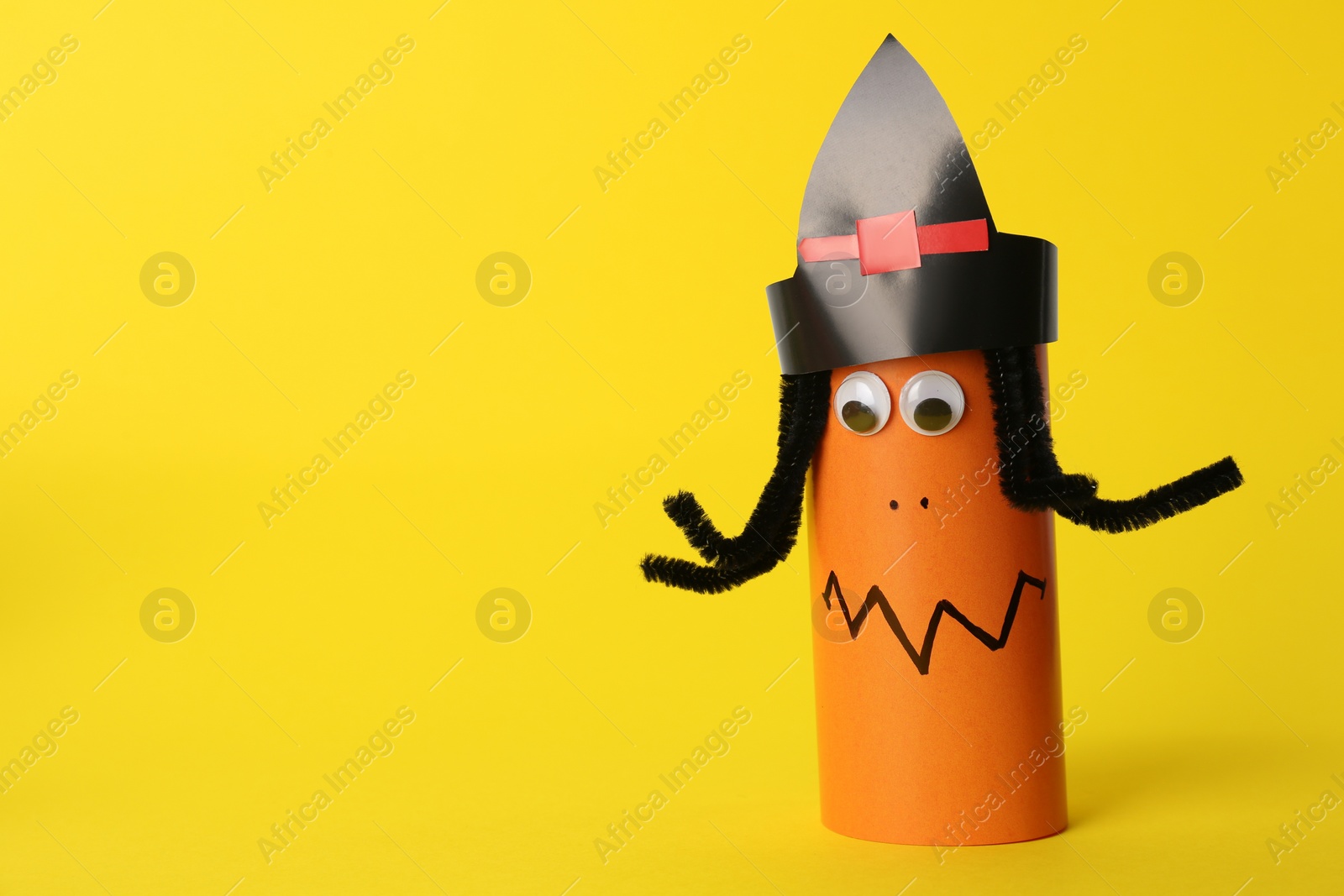 Photo of Funny orange monster on yellow background, space for text. Halloween decoration