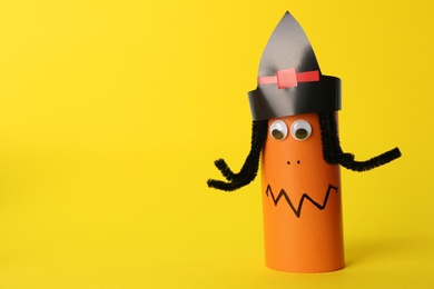 Photo of Funny orange monster on yellow background, space for text. Halloween decoration