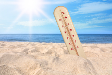 Image of Weather thermometer with high temperature on sandy beach near sea