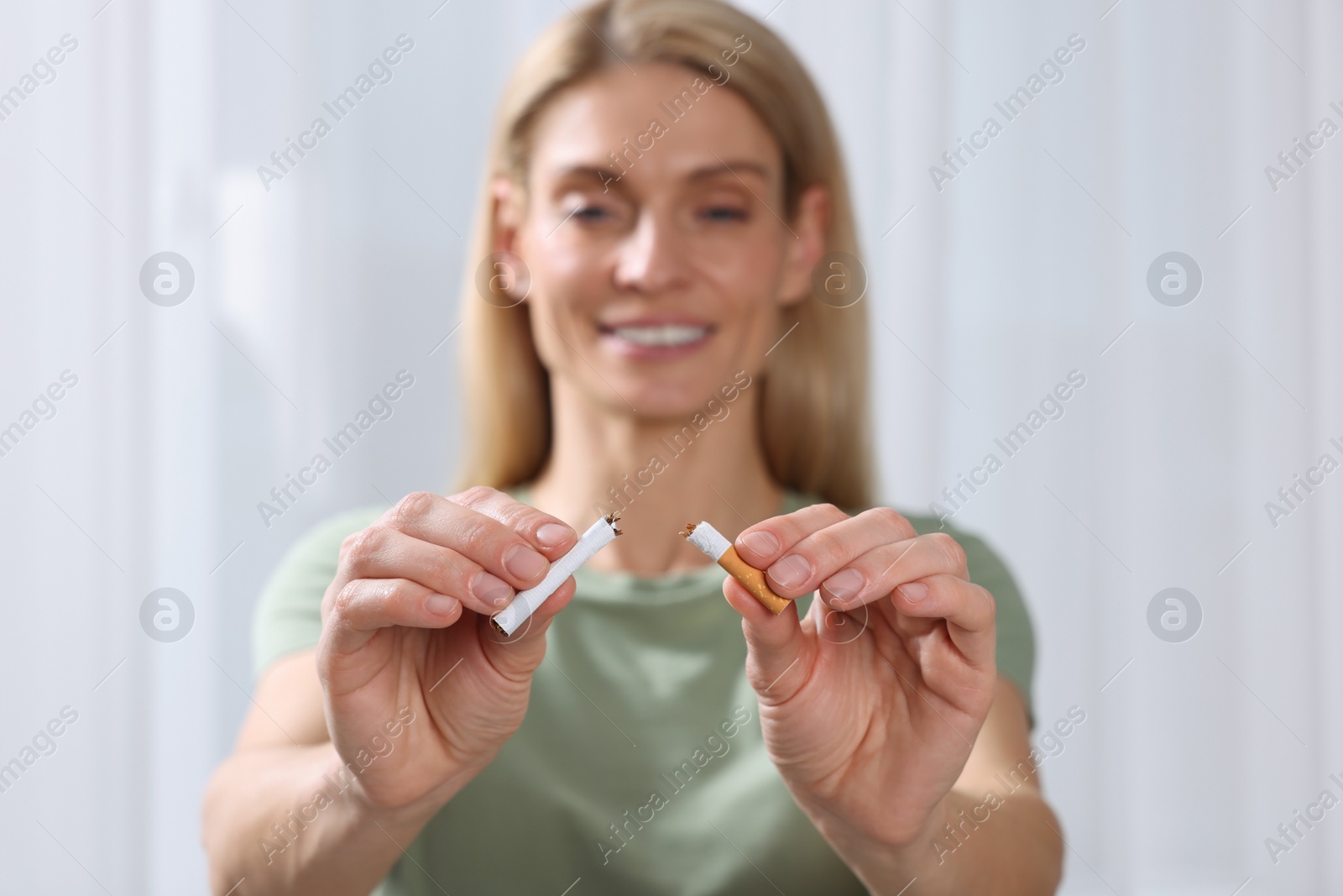 Photo of Woman with broken cigarette on light background, selective focus. Quitting smoking concept