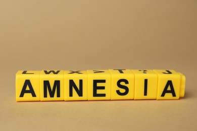 Photo of Yellow cubes with word Amnesia on light brown background