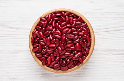 Photo of Raw red kidney beans in bowl on white wooden table, top view