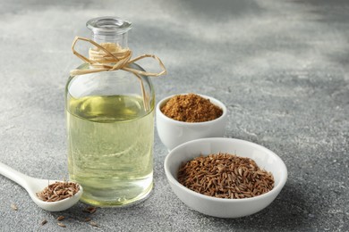 Caraway (Persian cumin) seeds, powder and essential oil on gray textured table, closeup