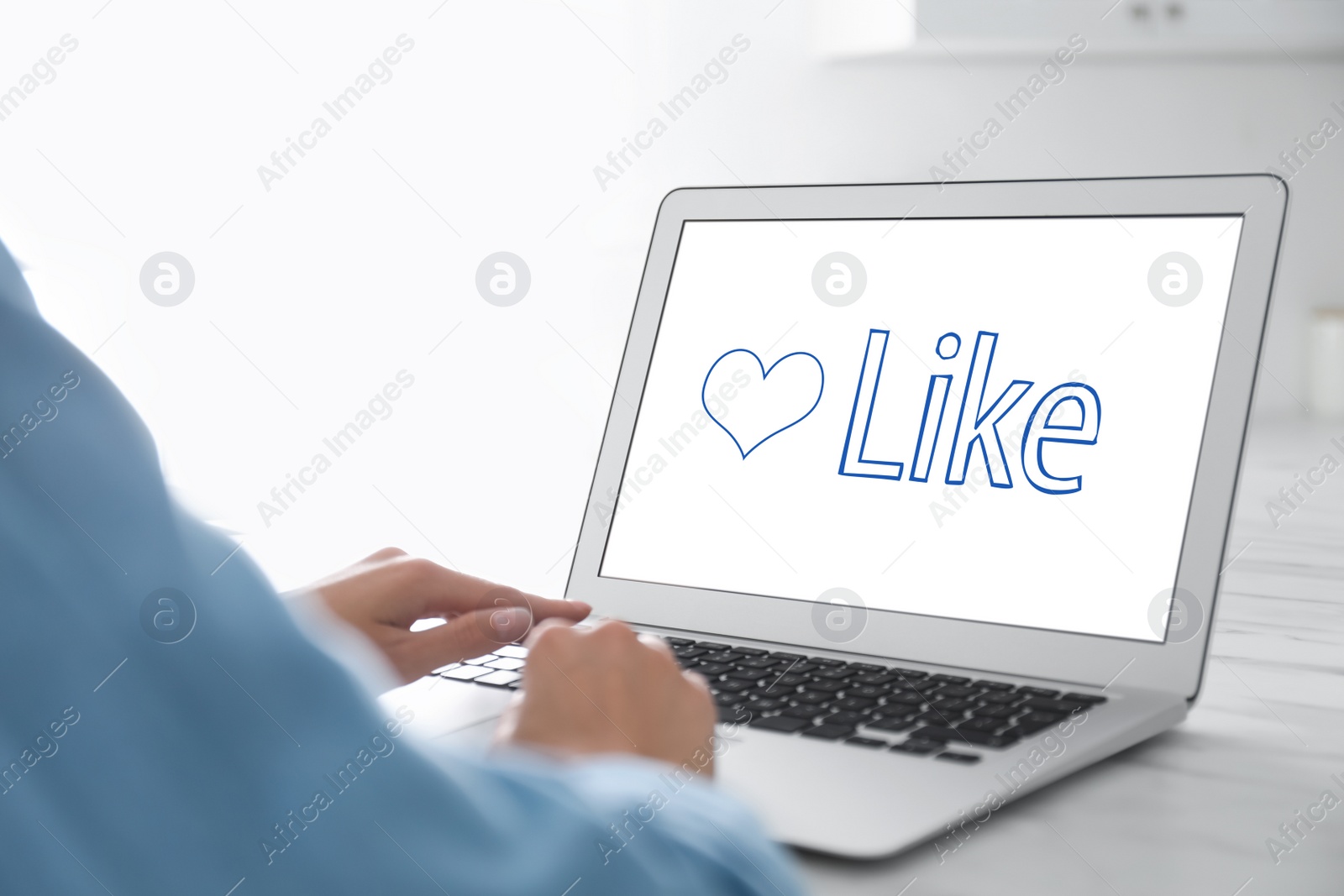 Image of Woman using laptop with word Like on screen at table, closeup