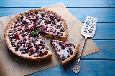 Photo of Delicious cut currant pie and spatula on blue wooden table