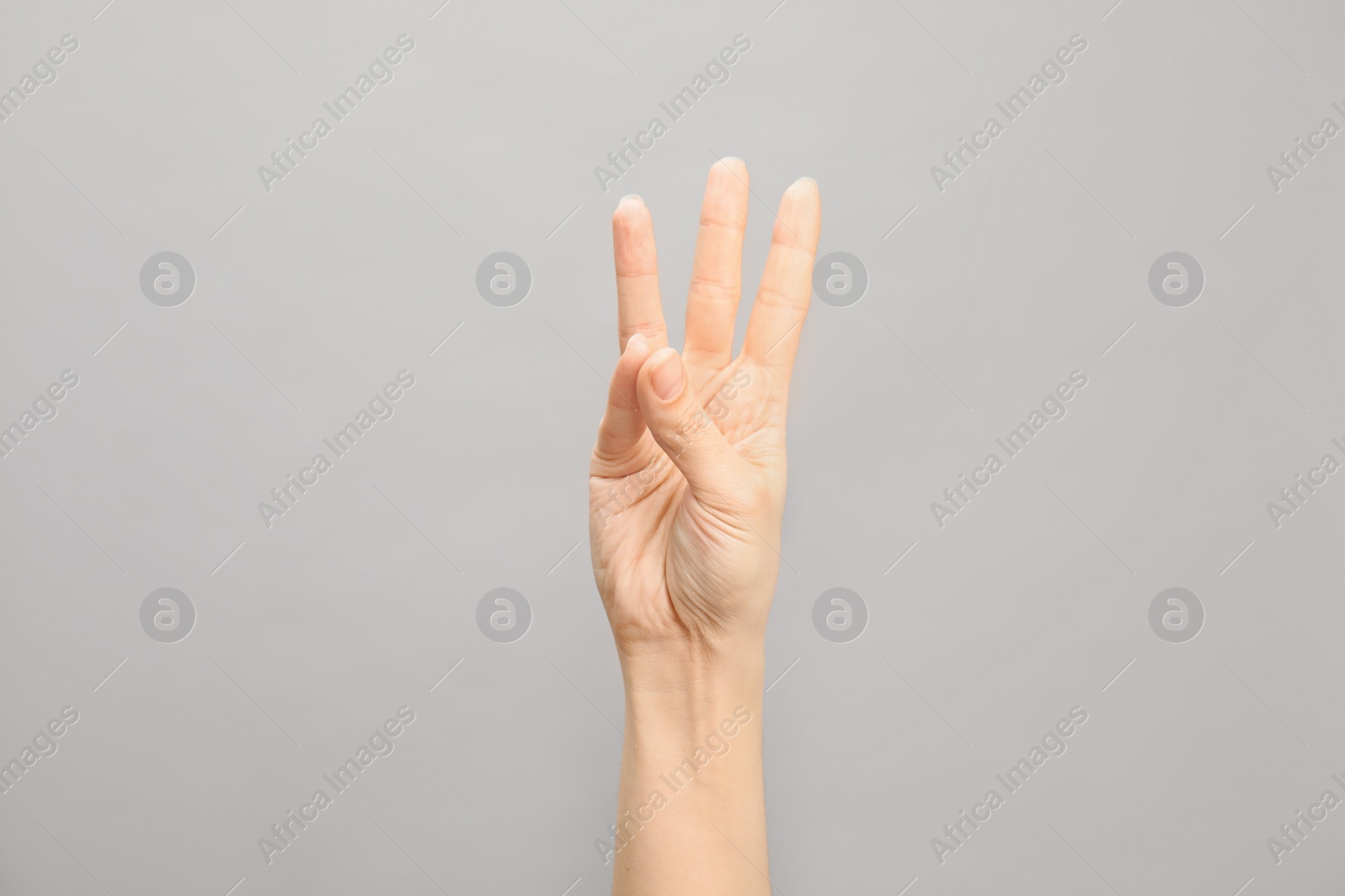 Photo of Woman showing number six on grey background, closeup. Sign language
