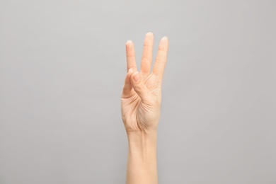 Photo of Woman showing number six on grey background, closeup. Sign language