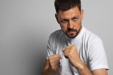Photo of Man ready to fight on grey background, space for text