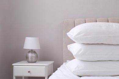 White soft pillows on bed and lamp in room