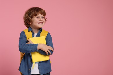 Photo of Happy schoolboy with backpack and books on pink background, space for text