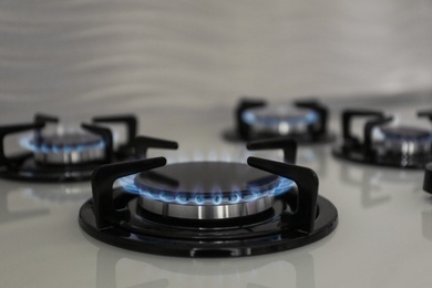 Photo of Gas burners with blue flame on modern stove. Space for text