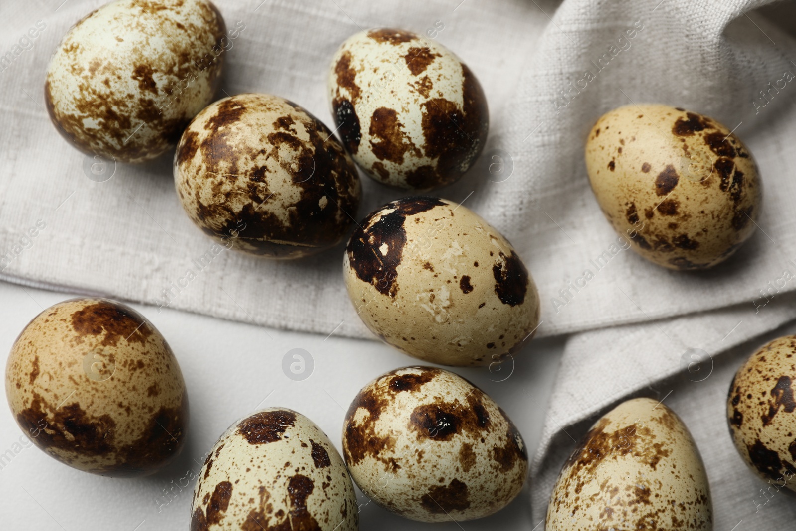 Photo of Many speckled quail eggs on white table, flat lay