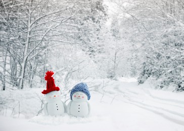 Image of Cute decorative snowmen in snowy forest, space for text