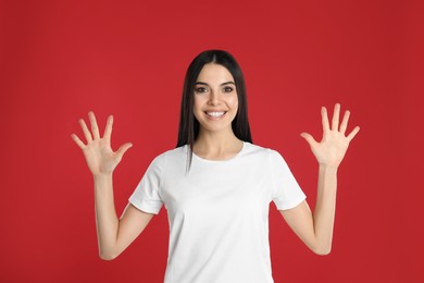 Woman showing number ten with her hands on red background