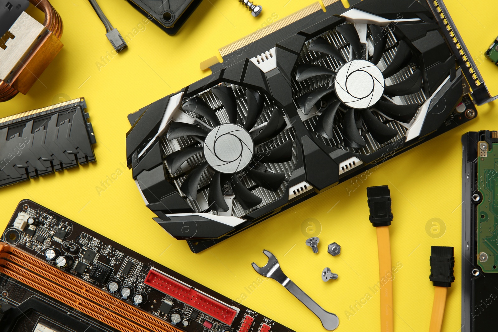 Photo of Graphics card and other computer hardware on yellow background, flat lay