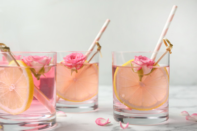 Photo of Refreshing drink with lemon and rose on white marble table