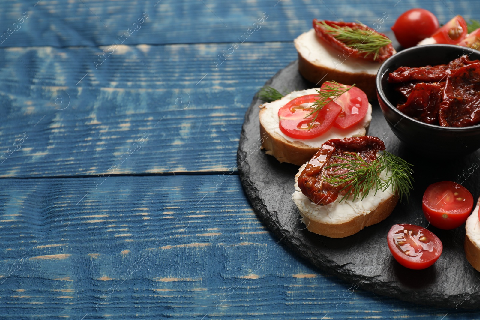 Photo of Delicious bruschettas with ricotta cheese, tomatoes, and dill on blue wooden table, closeup. Space for text