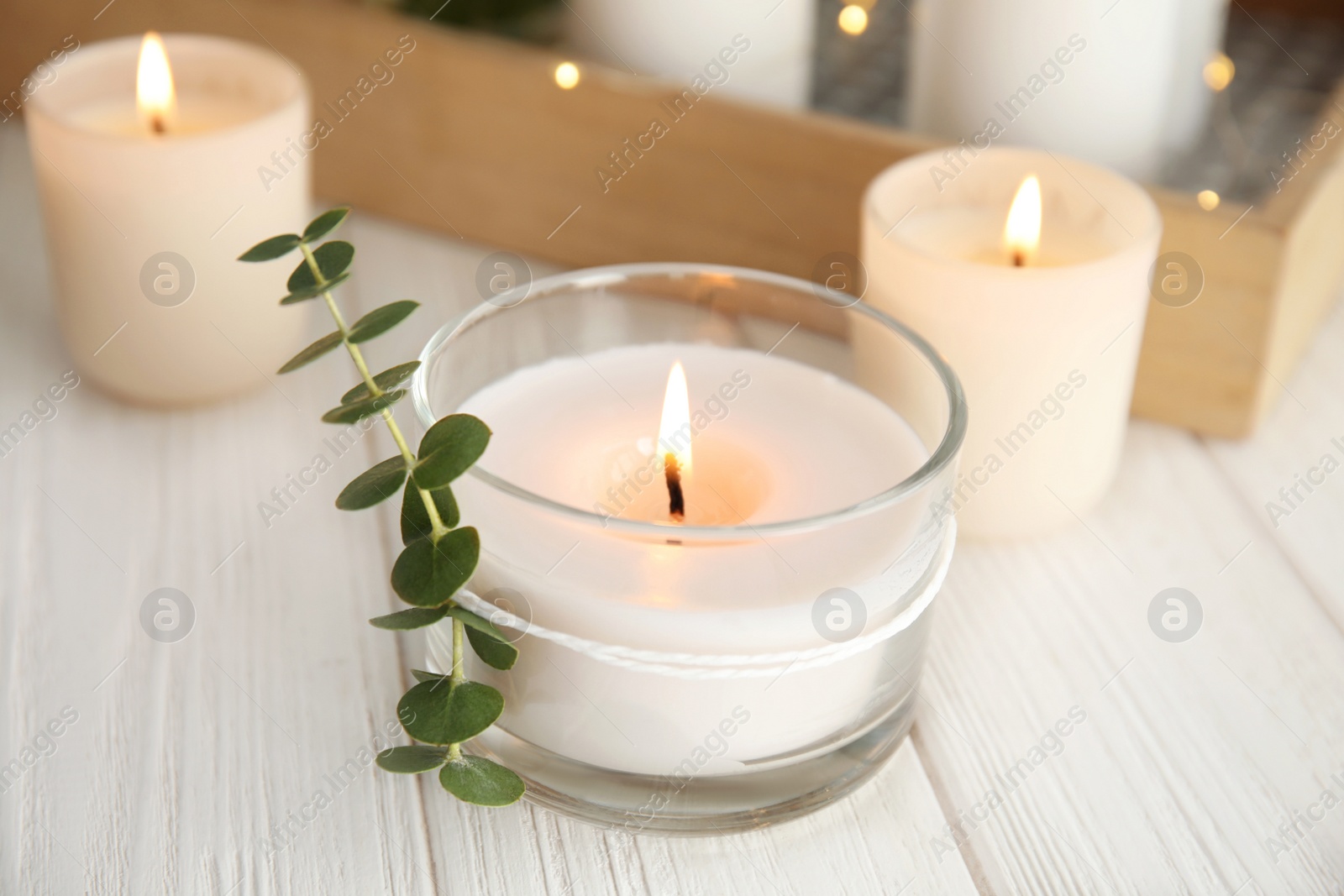 Photo of Burning aromatic candle and eucalyptus branch on table