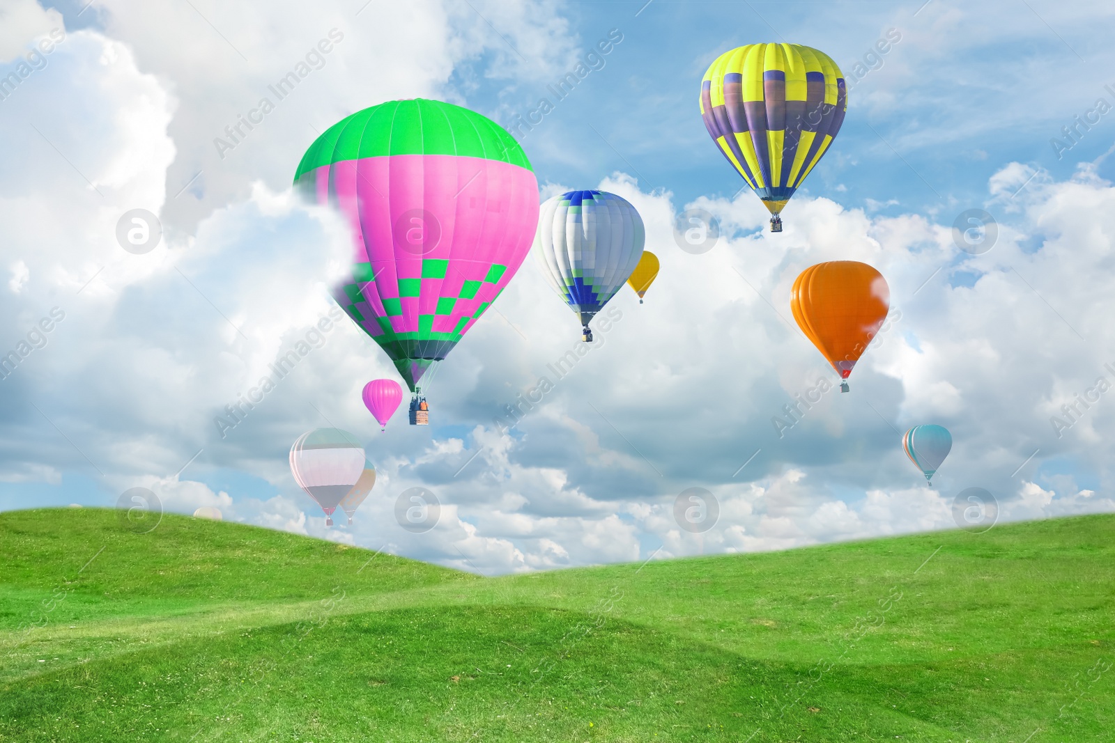 Image of Fantastic dreams. Hot air balloons in sky with fluffy clouds over green meadow