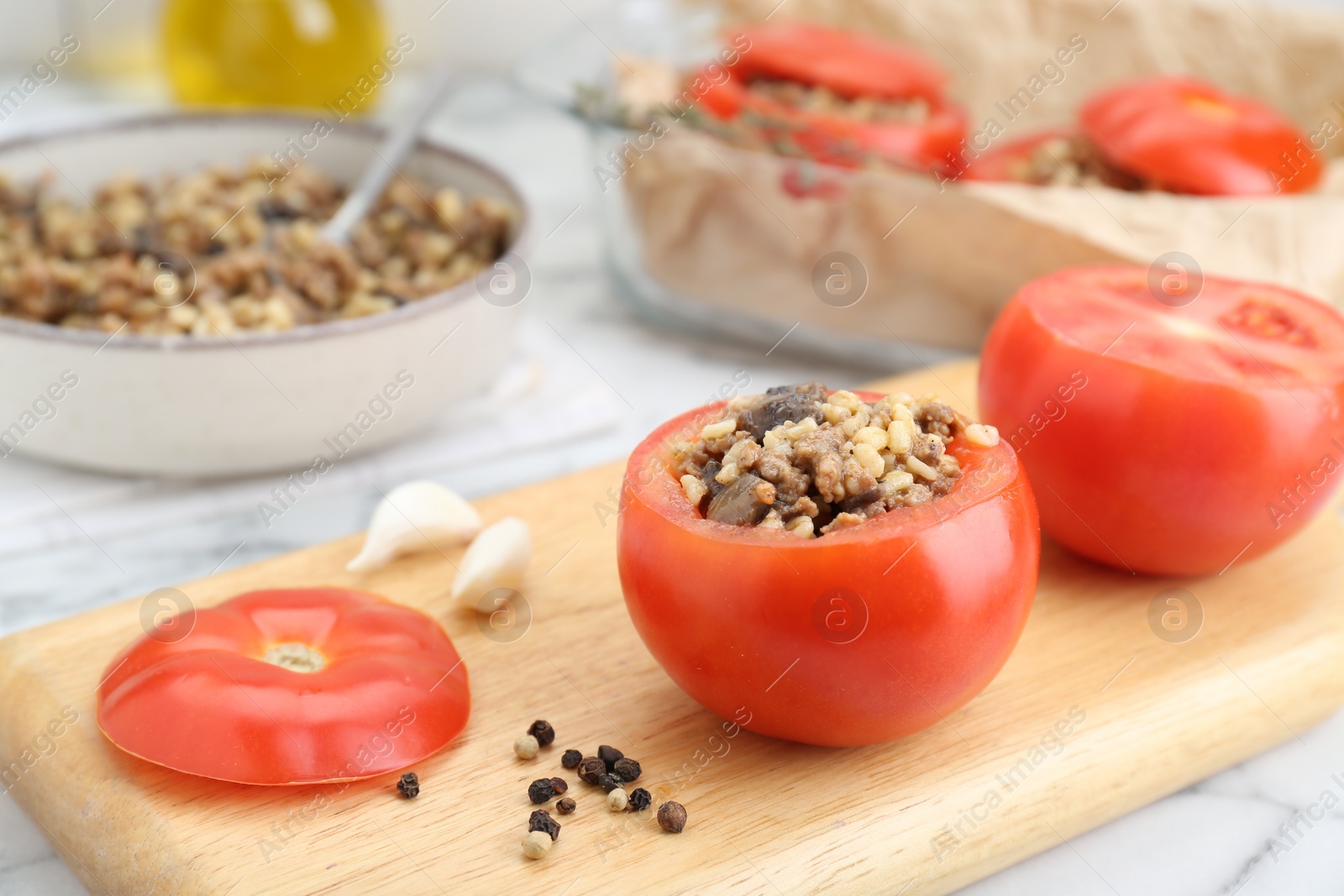 Photo of Preparing stuffed tomatoes with minced beef, bulgur and mushrooms on white marble table, closeup