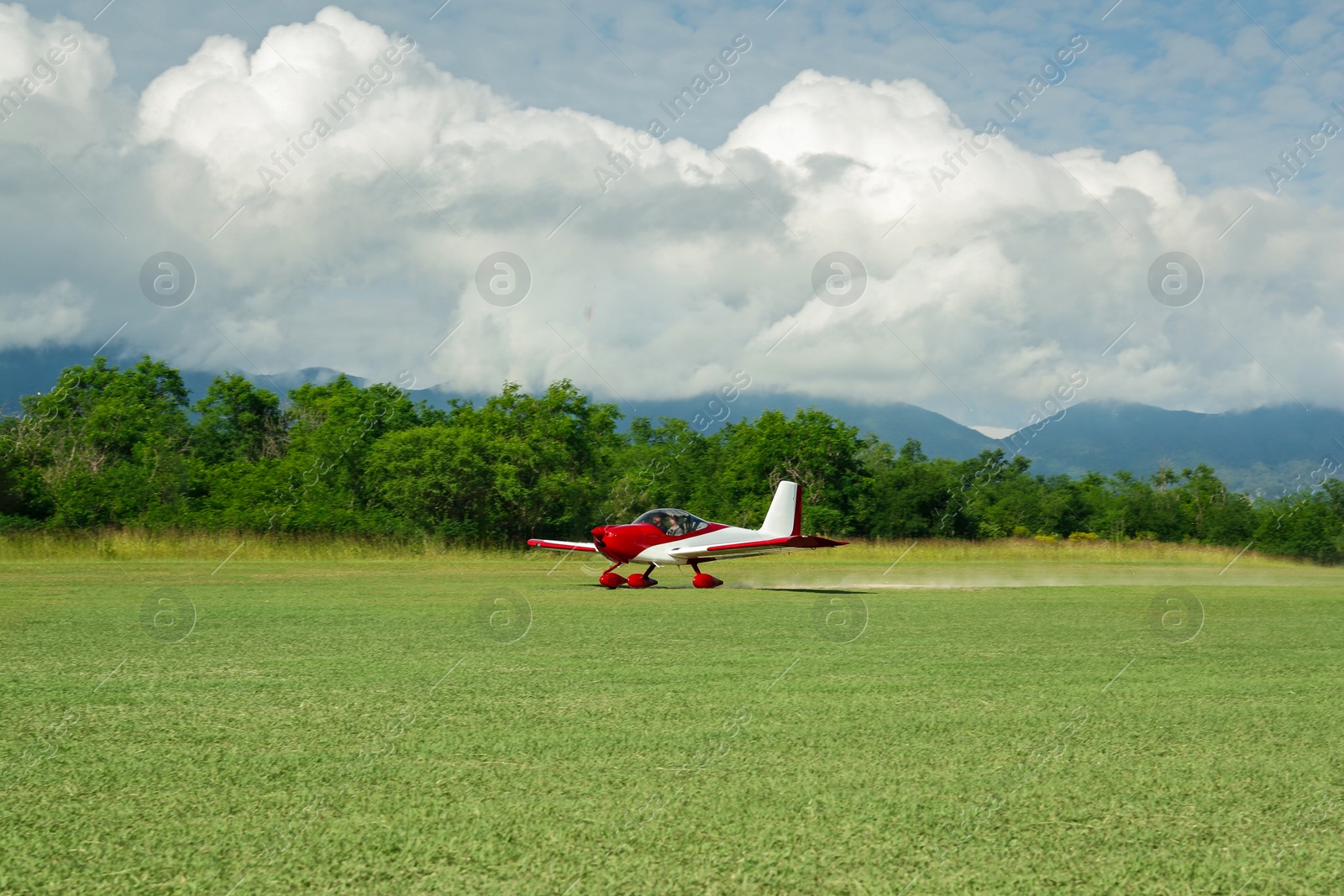 Photo of Modern airplane on green grass against mountains background