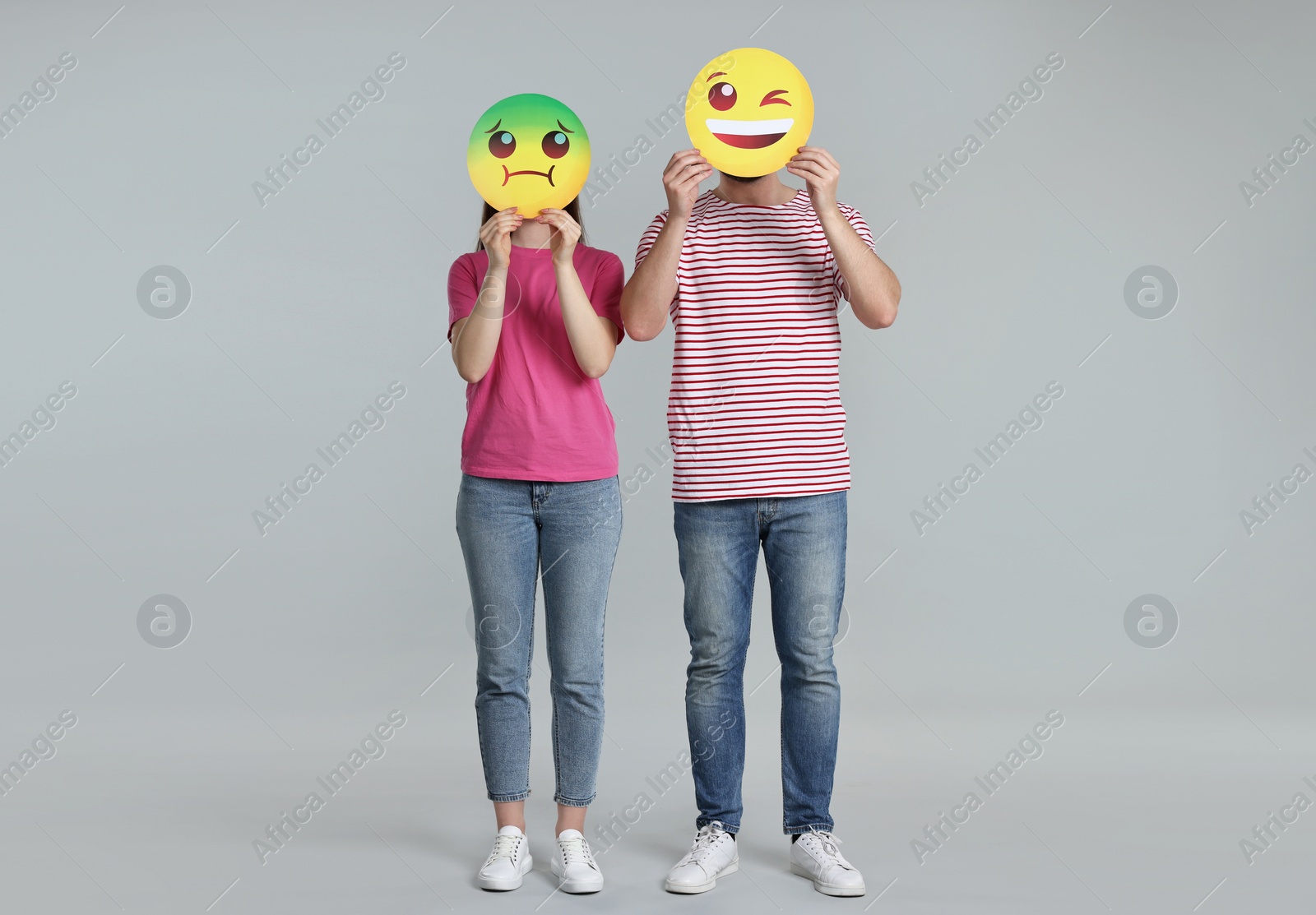 Photo of People covering faces with emoticons on grey background