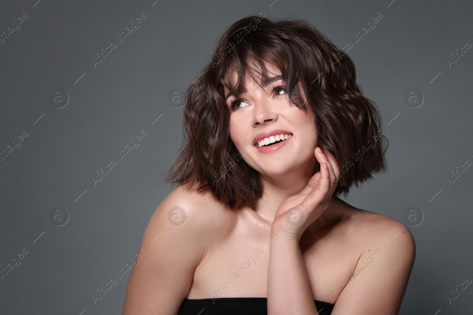 Photo of Portrait of beautiful young woman with wavy hairstyle on grey background. Space for text