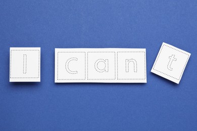Photo of Motivation concept. Changing phrase from I Can't into I Can by removing paper with letter T on blue background, top view