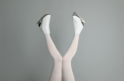 Photo of Woman in elegant white ice skates on grey background, closeup of legs