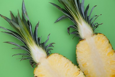 Photo of Halves of ripe pineapple on light green background, flat lay