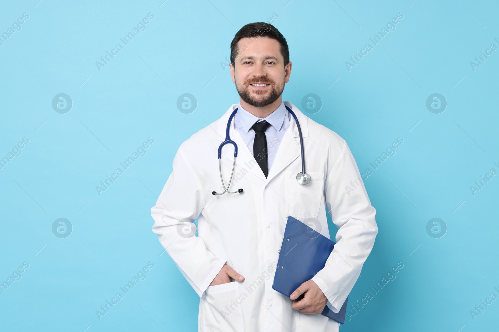 Photo of Smiling doctor with clipboard on light blue background