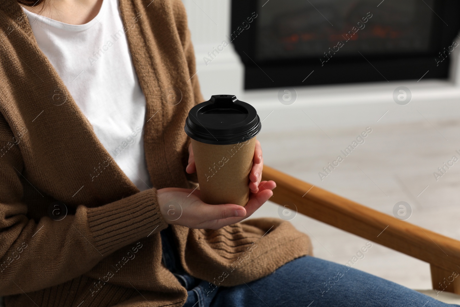 Photo of Woman holding takeaway cardboard cup indoors, closeup. Coffee to go