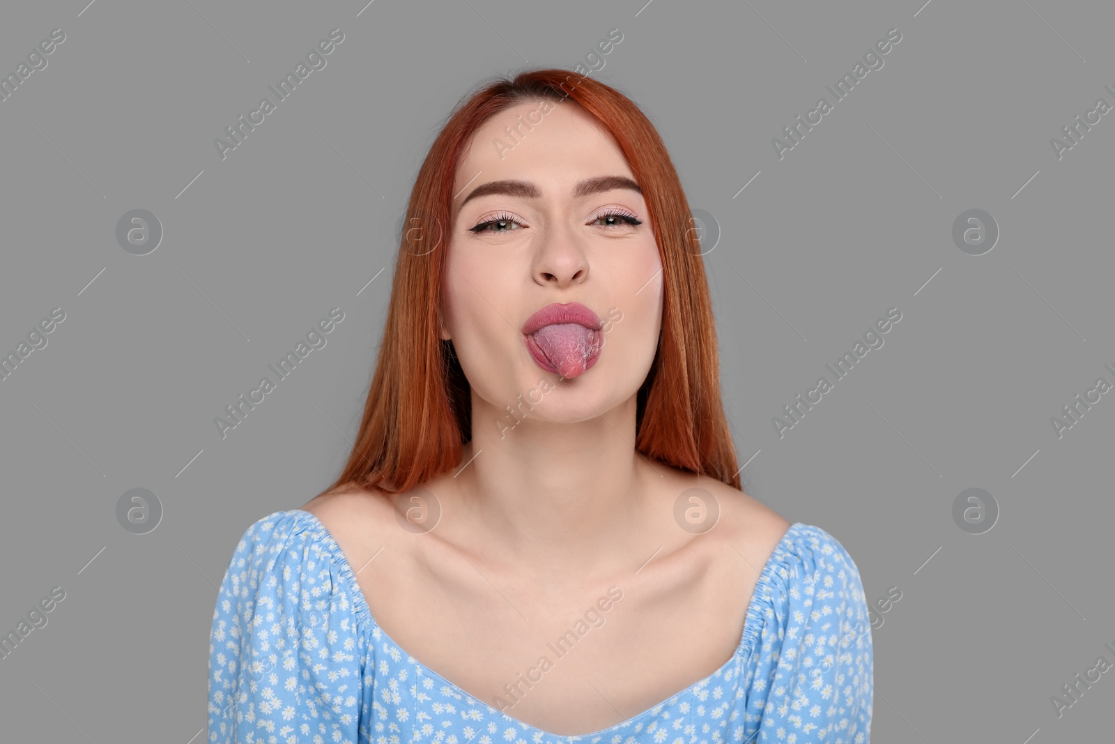 Photo of Happy woman showing her tongue on gray background