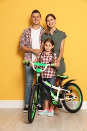 Photo of Portrait of parents and their daughter with bicycle near color wall