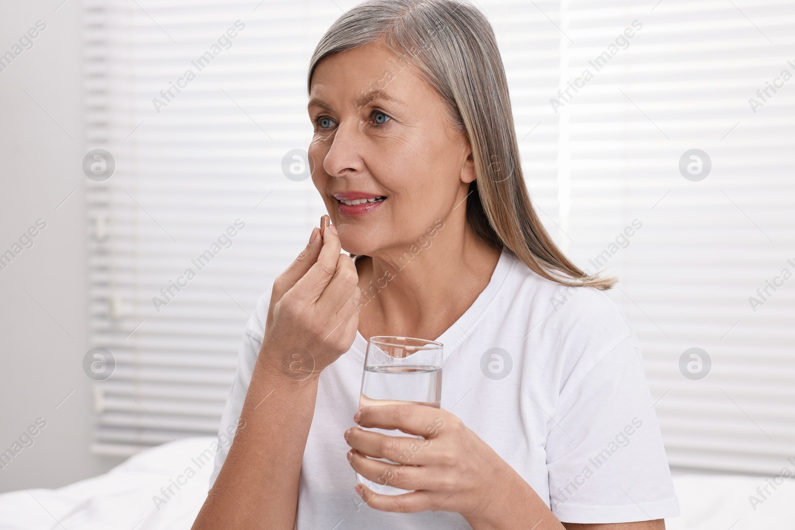 Photo of Beautiful woman taking vitamin pill at home