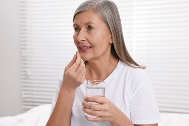 Photo of Beautiful woman taking vitamin pill at home